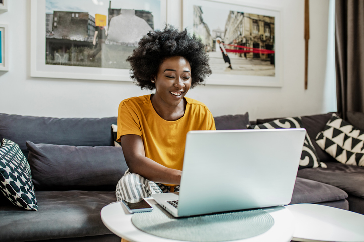 A young African-American woman uses a laptop in her modern apartment