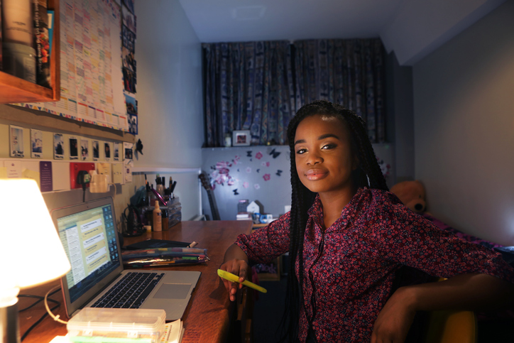 Student working at desk in bedroom at night