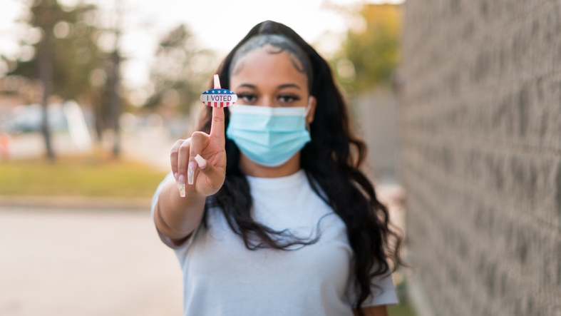 Young woman holds up "I voted" sticker