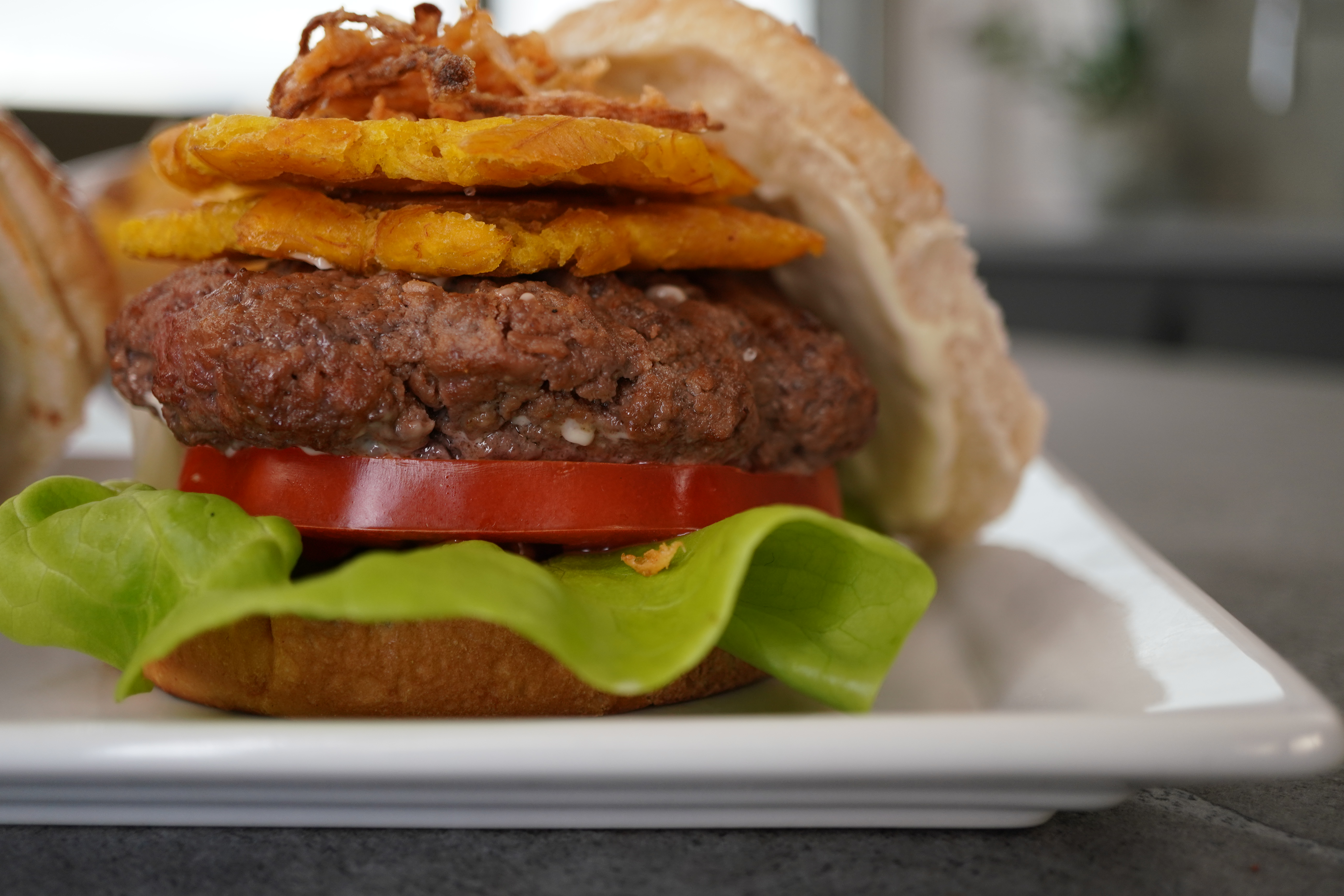 Malta Marinated Beef Burger topped with Fried Plantains