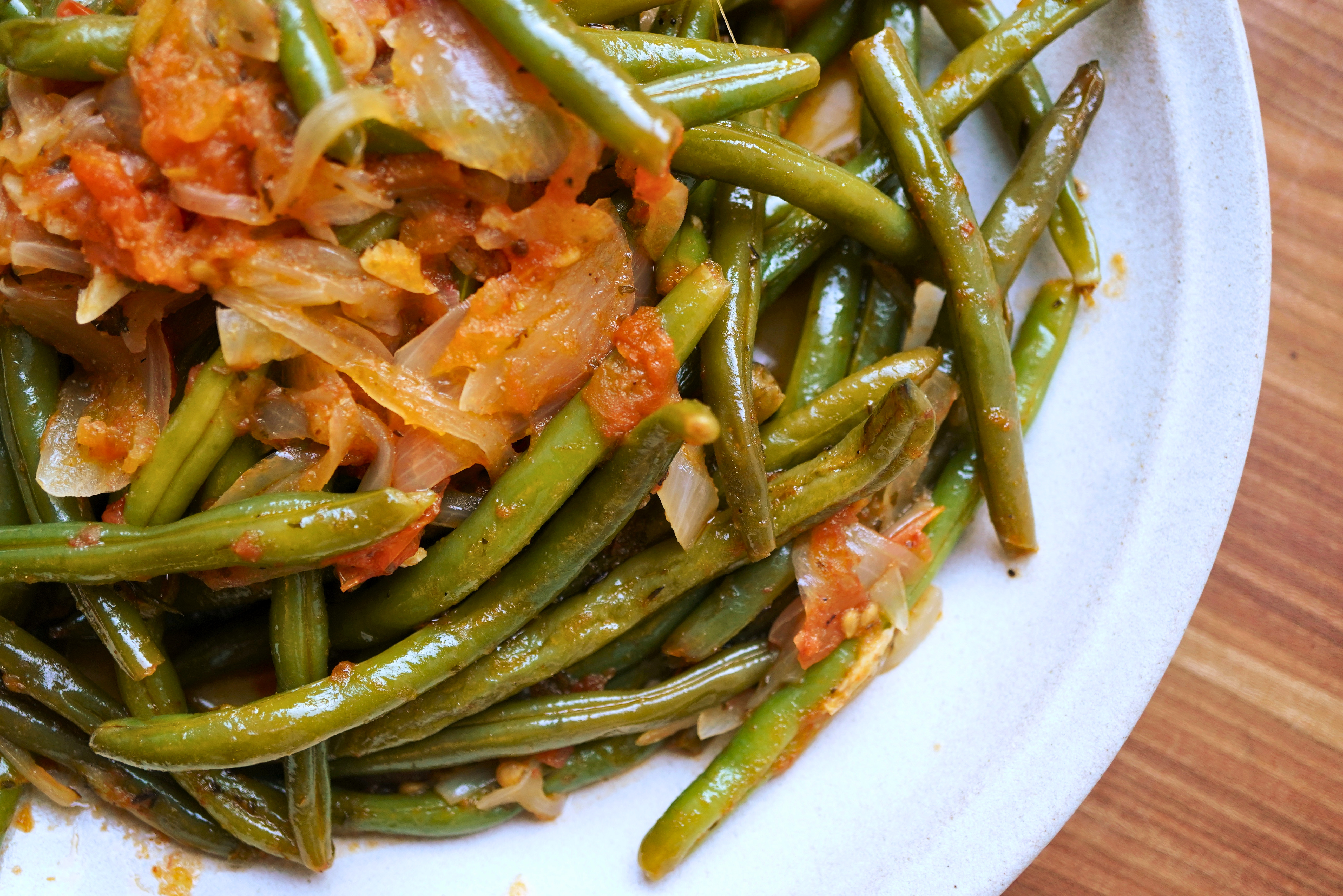 Plate of cooked green beans and carrots in a savory sauce.