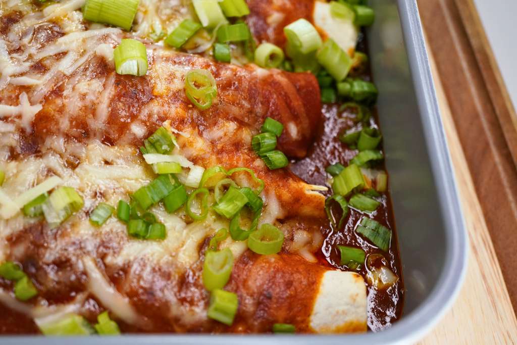 A baked dish with melted cheese, green onions, and a tomato-based sauce.