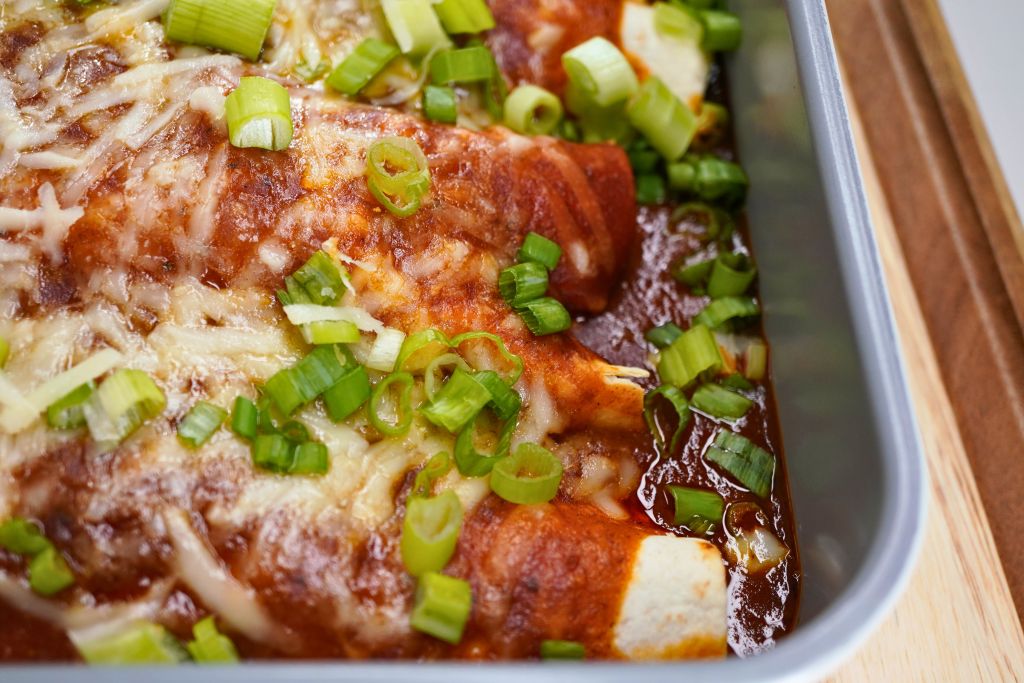 A baked dish with melted cheese, green onions, and a tomato-based sauce.