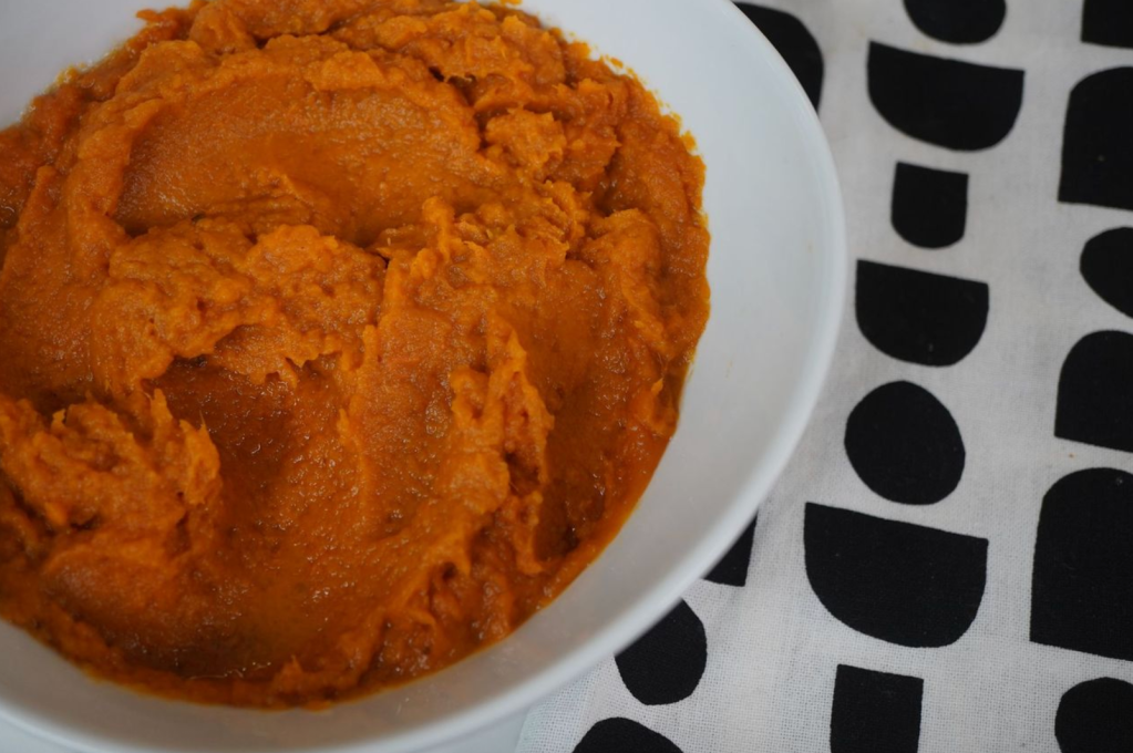 A plate of orange-colored mashed sweet potatoes or yams.