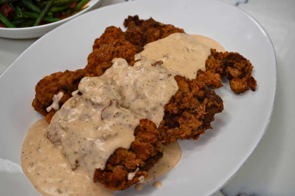 A plate of crispy fried chicken with a creamy white gravy sauce.
