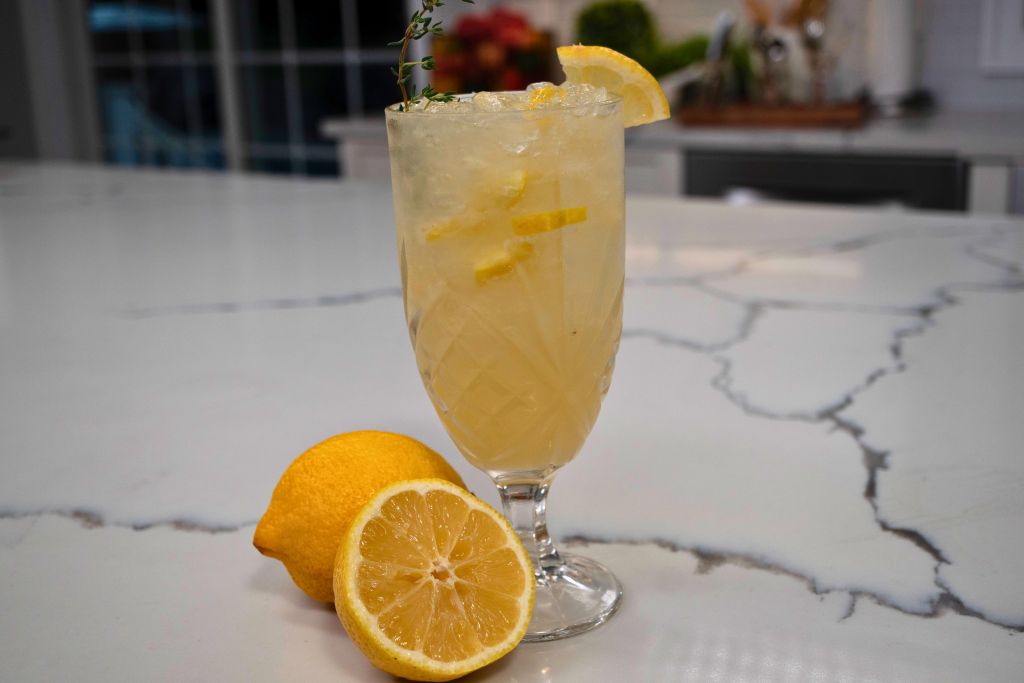 A glass of lemonade garnished with a lemon slice on a marble countertop.