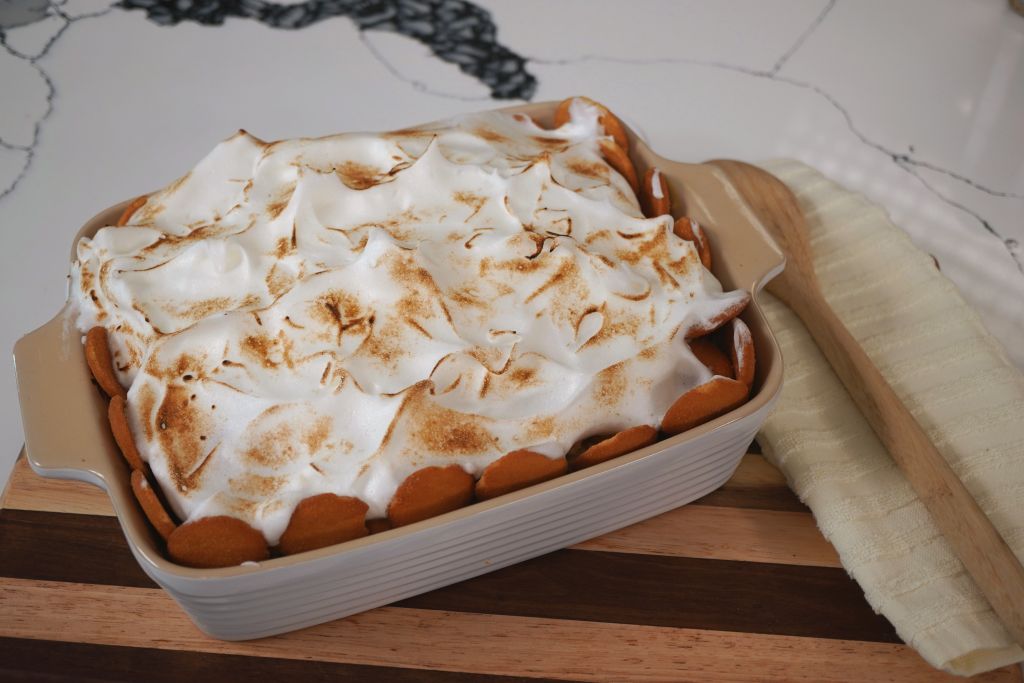 A white ceramic baking dish filled with a creamy, meringue-topped dessert, likely a lemon meringue pie or similar.