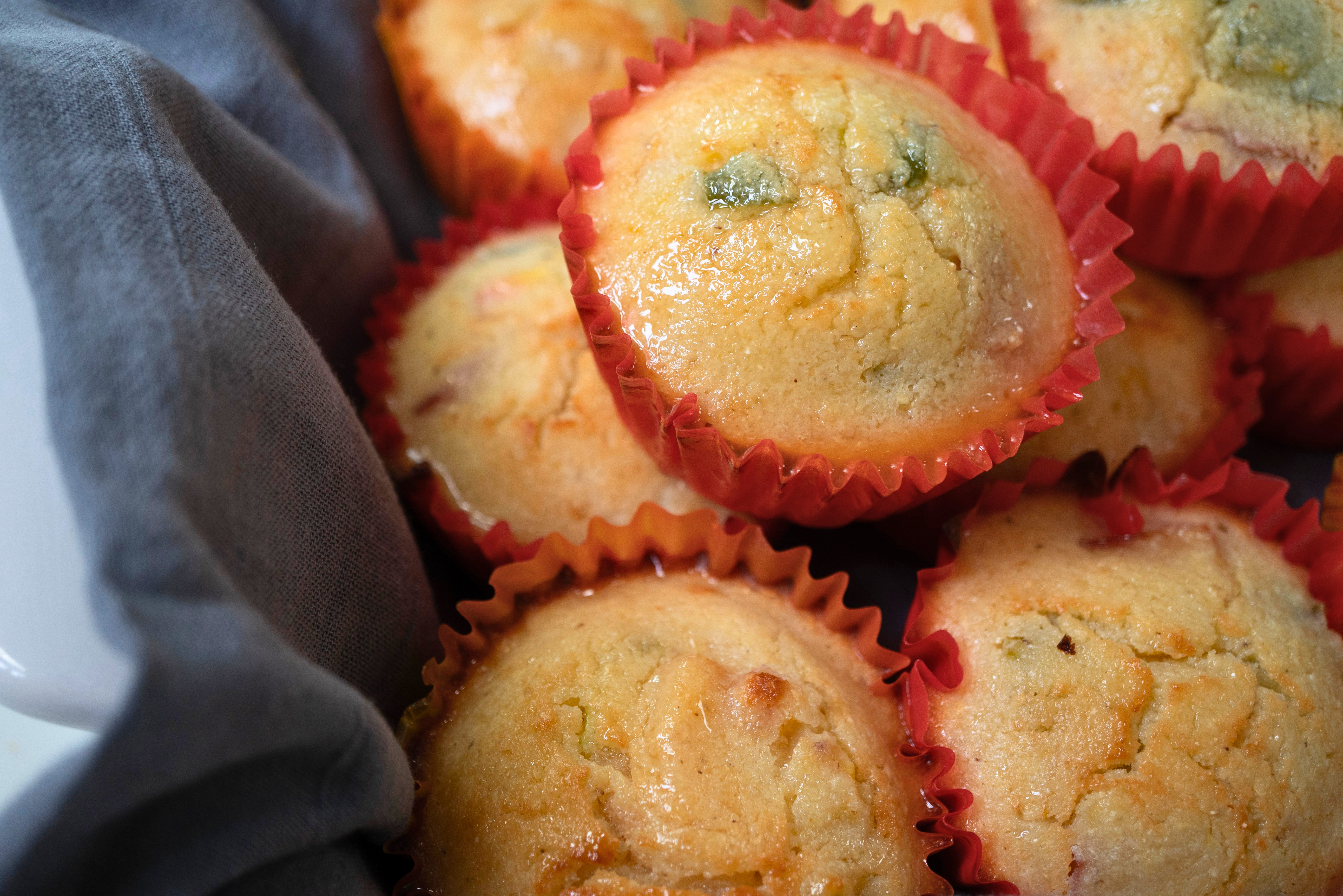 Freshly baked muffins in red paper liners, with a golden brown top and visible crumbs.