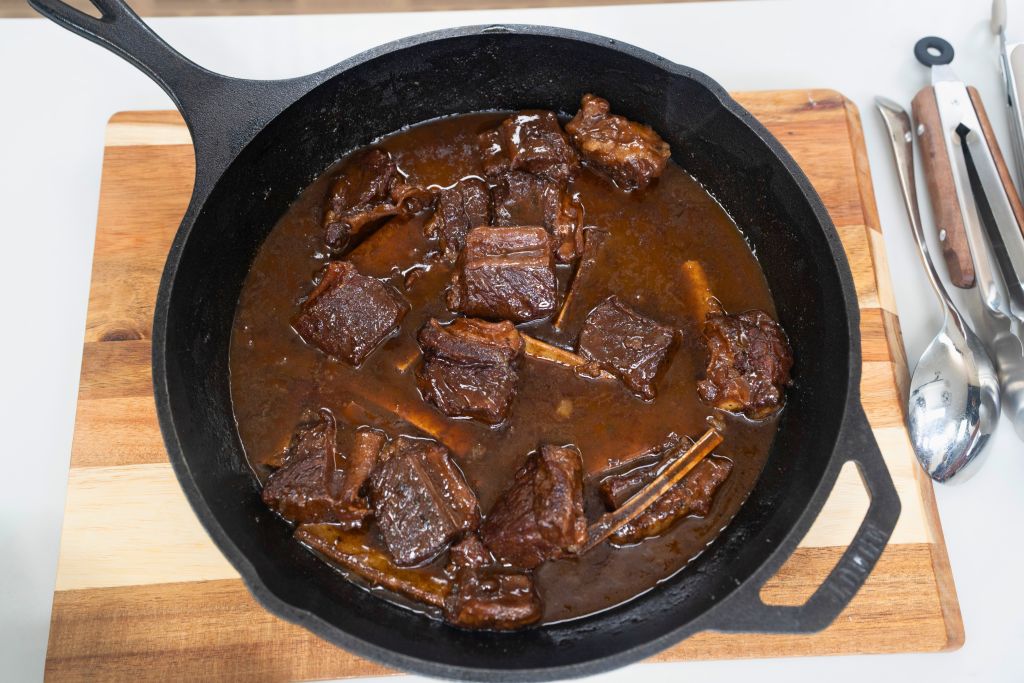 A cast iron skillet filled with a hearty beef stew, with chunks of tender meat and a rich, savory sauce.