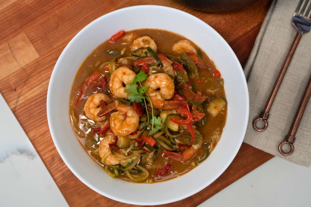 A white bowl filled with a savory shrimp and vegetable stew, garnished with fresh cilantro.