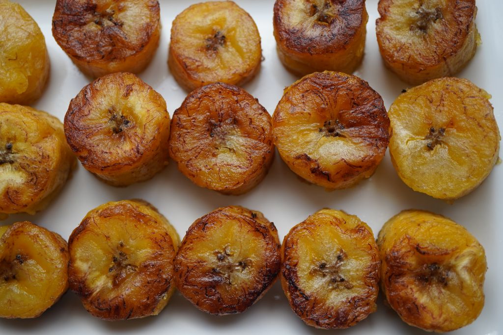 Assorted fried plantain slices on a white surface, with varying degrees of caramelization and browning.