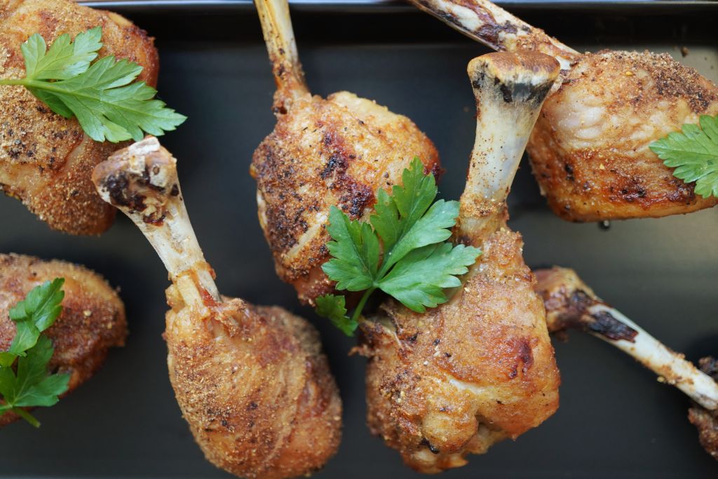 Crispy fried chicken drumsticks garnished with fresh parsley on a dark background.